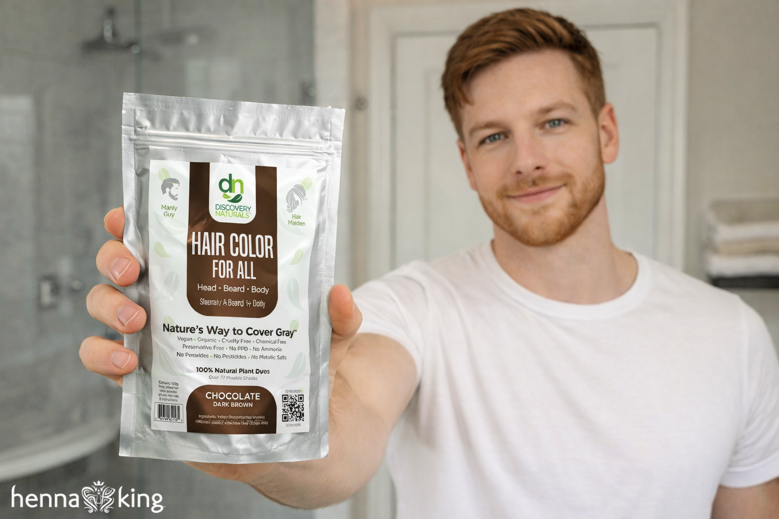 A man holding Henna King hair dye in his bathroom.